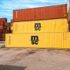 A stack of colorful shipping containers, with a prominent yellow MSC container in the foreground against a blue sky.